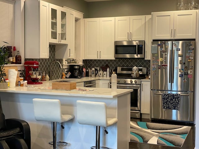 kitchen with light countertops, appliances with stainless steel finishes, backsplash, and white cabinets