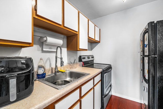 kitchen featuring white cabinetry, hardwood / wood-style flooring, sink, stainless steel electric range oven, and black fridge