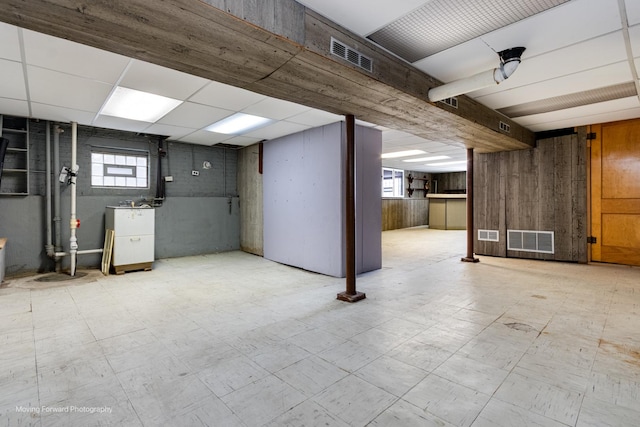 basement with visible vents, a drop ceiling, and tile patterned floors