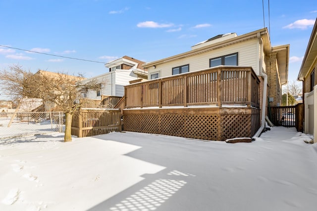 snow covered rear of property featuring fence and a wooden deck