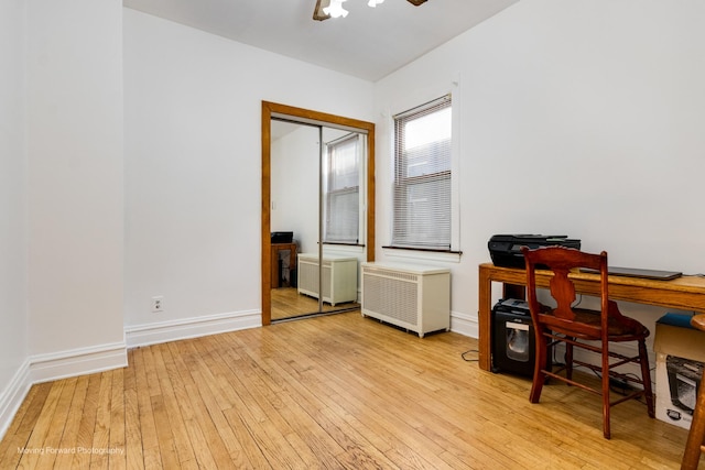 office space with baseboards, radiator, and light wood-style floors