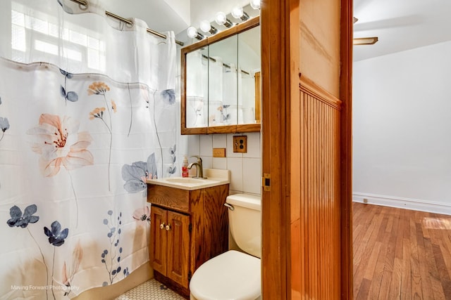 full bath with toilet, a shower with shower curtain, wood finished floors, vanity, and tile walls