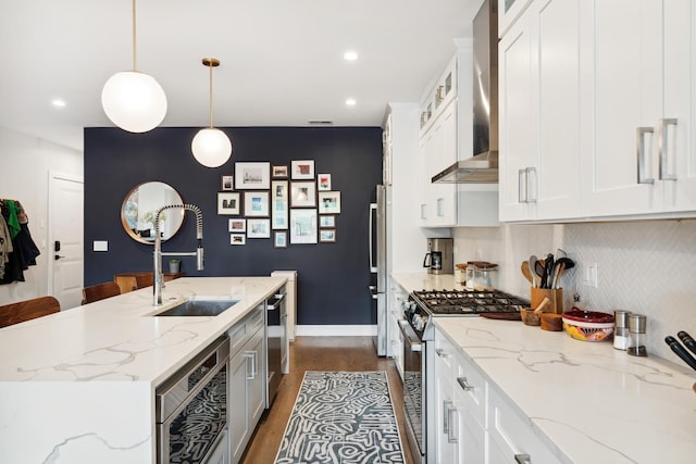 kitchen with stainless steel appliances, dark wood-type flooring, a sink, white cabinets, and wall chimney exhaust hood