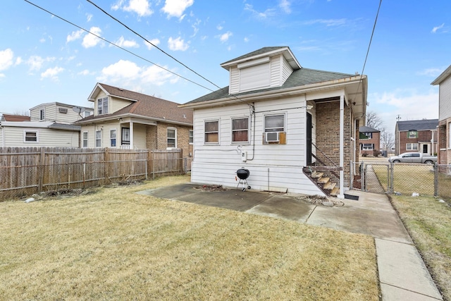 rear view of property featuring a fenced backyard, a gate, a lawn, and brick siding