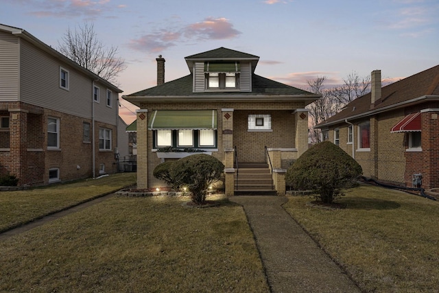 bungalow-style home featuring brick siding and a yard