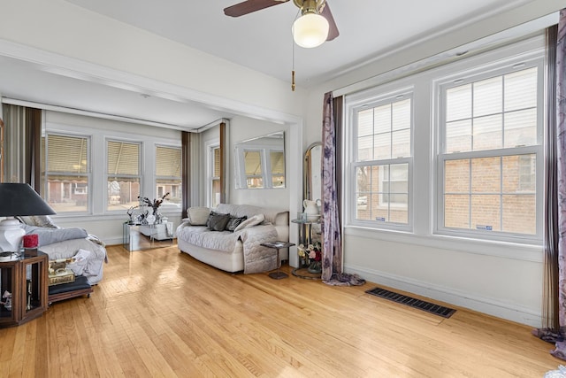 interior space with a ceiling fan, wood finished floors, visible vents, and baseboards