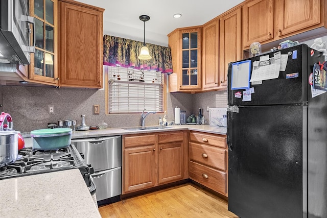 kitchen featuring brown cabinets, light countertops, a sink, and freestanding refrigerator