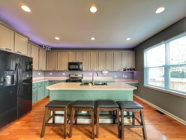 kitchen featuring recessed lighting, a sink, visible vents, a kitchen breakfast bar, and black appliances