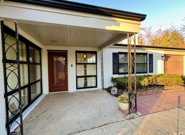 entrance to property with brick siding and a patio area