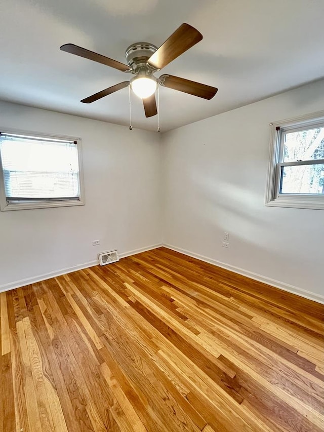 unfurnished room featuring baseboards, light wood-type flooring, visible vents, and a healthy amount of sunlight