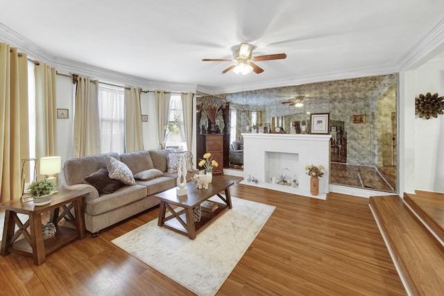 living area with a fireplace with flush hearth, crown molding, and wood finished floors