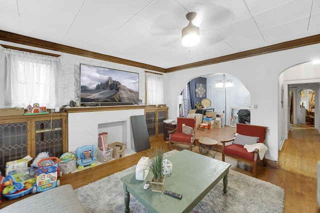 living room with crown molding, wood finished floors, arched walkways, and baseboards