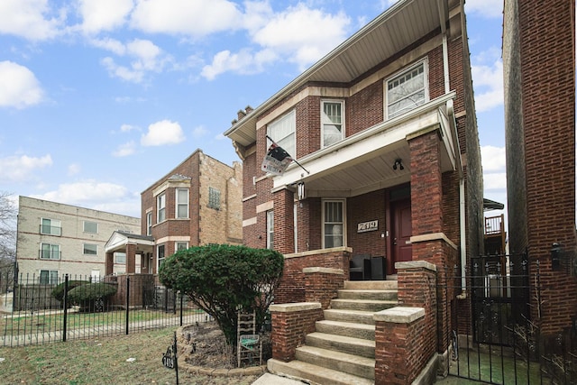 multi unit property featuring a porch, fence, and brick siding