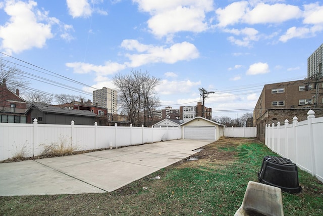 view of yard with a fenced backyard, a detached garage, and an outdoor structure