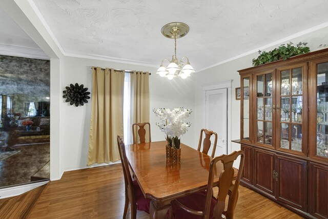 dining space with a chandelier, crown molding, and light wood-type flooring