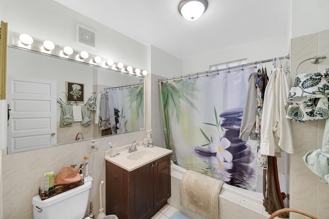 bathroom featuring tiled shower / bath combo, toilet, tile walls, and vanity