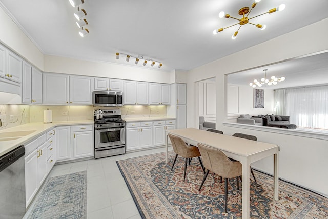 kitchen featuring stainless steel appliances, white cabinets, a chandelier, pendant lighting, and sink