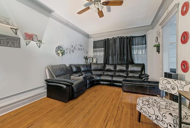 living room featuring hardwood / wood-style flooring, crown molding, and ceiling fan