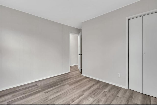 unfurnished bedroom with light wood-type flooring and a closet