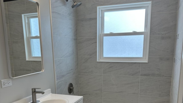 bathroom featuring vanity, a tile shower, and a wealth of natural light