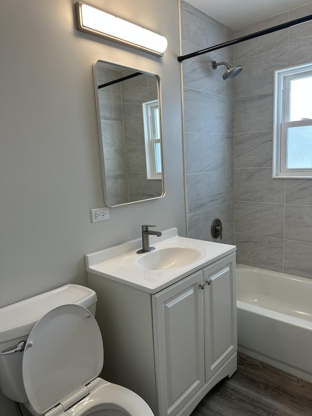 full bathroom featuring hardwood / wood-style flooring, vanity, toilet, and tiled shower / bath