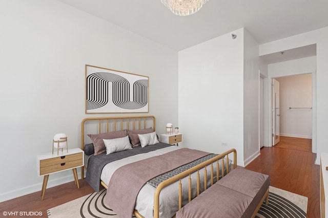 bedroom featuring wood finished floors, baseboards, and a notable chandelier