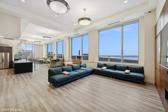 living room featuring light wood-type flooring, recessed lighting, and a raised ceiling