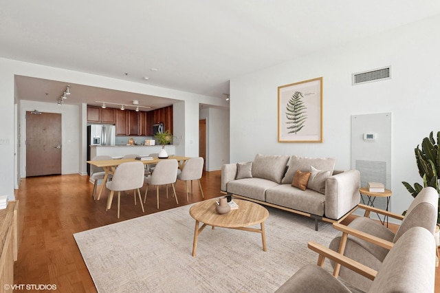 living room featuring track lighting, dark wood-type flooring, and visible vents