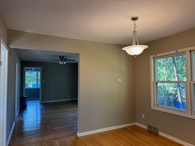 empty room with a textured ceiling, dark hardwood / wood-style floors, and ceiling fan