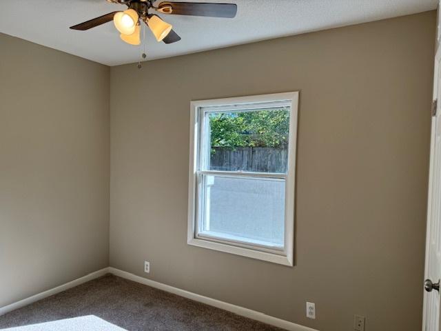 carpeted spare room featuring ceiling fan