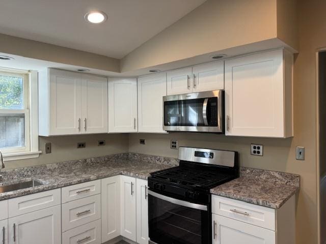 kitchen with white cabinetry, stainless steel appliances, vaulted ceiling, and sink