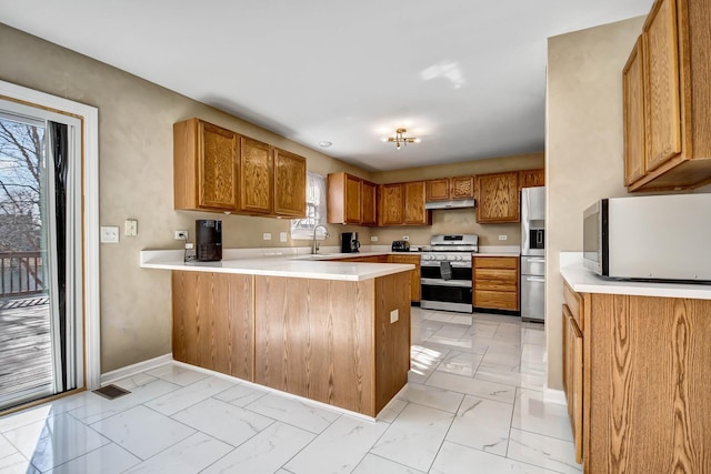 kitchen with a peninsula, marble finish floor, appliances with stainless steel finishes, and a sink