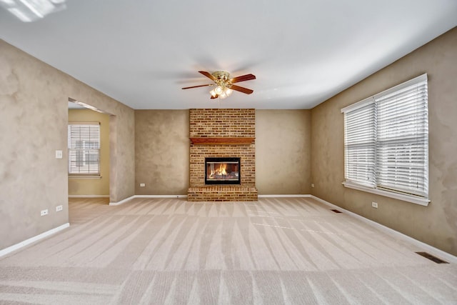 unfurnished living room featuring a ceiling fan, visible vents, baseboards, a fireplace, and carpet flooring