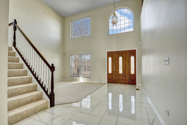 foyer with baseboards, marble finish floor, and stairs