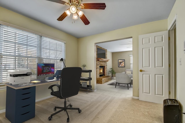 office featuring light carpet, a fireplace, baseboards, and a ceiling fan