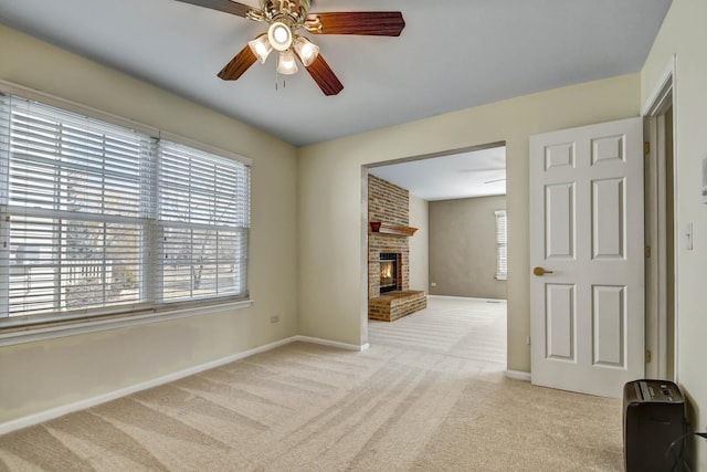 unfurnished living room with carpet flooring, ceiling fan, a fireplace, and baseboards