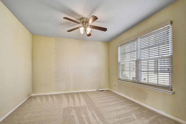 carpeted spare room with a ceiling fan and baseboards