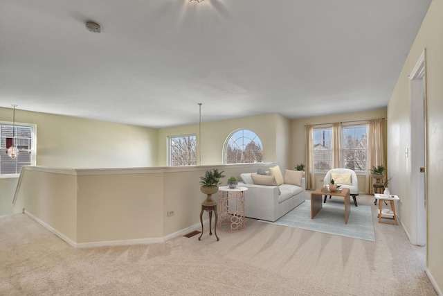 living area with carpet floors, a healthy amount of sunlight, and a chandelier