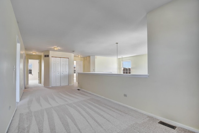 empty room with light colored carpet, visible vents, and baseboards