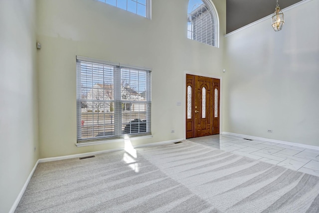 foyer with visible vents, baseboards, and a high ceiling