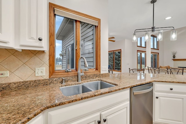 kitchen with sink, white cabinetry, light stone counters, and decorative light fixtures