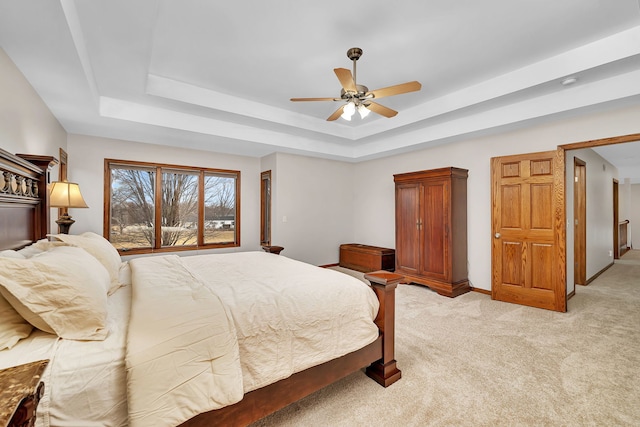 carpeted bedroom featuring ceiling fan and a tray ceiling