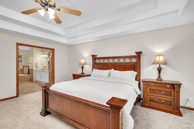 carpeted bedroom with ensuite bathroom, ceiling fan, and a tray ceiling