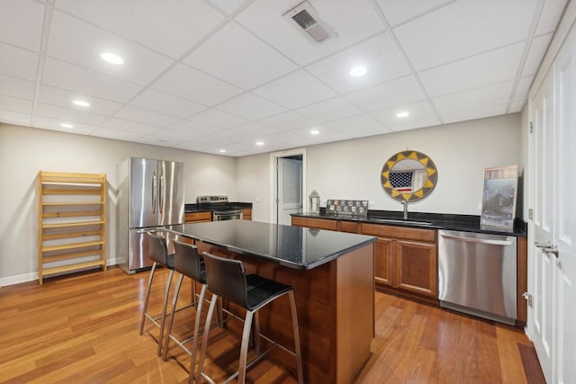 kitchen with visible vents, brown cabinets, a kitchen breakfast bar, a center island, and stainless steel appliances