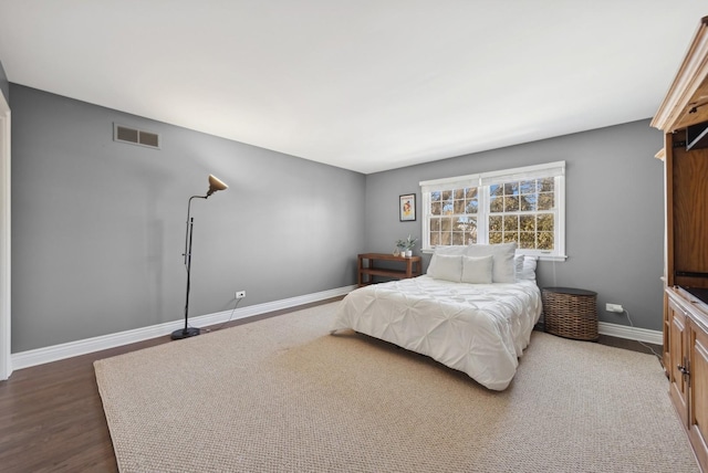 bedroom with dark wood-style floors, visible vents, and baseboards