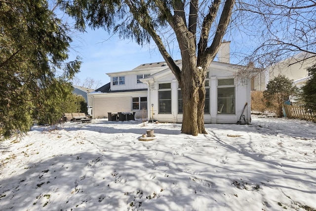 snow covered rear of property with a chimney