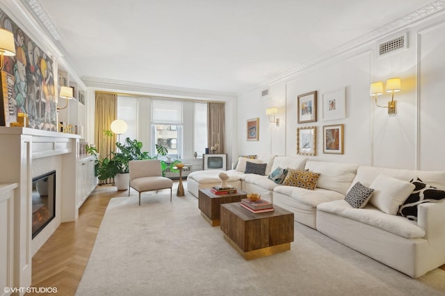 living room featuring a glass covered fireplace, visible vents, and crown molding