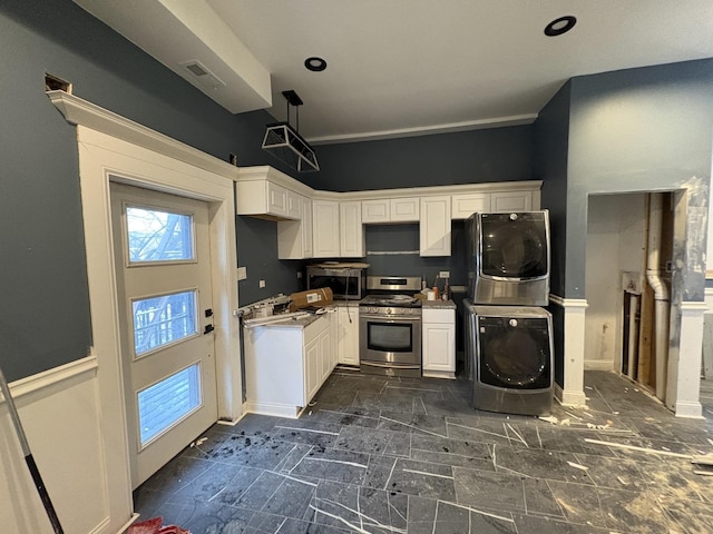 kitchen featuring white cabinetry, stainless steel appliances, pendant lighting, and stacked washer / drying machine