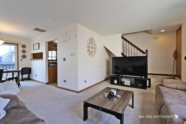 living room featuring stairway, light carpet, visible vents, and baseboards