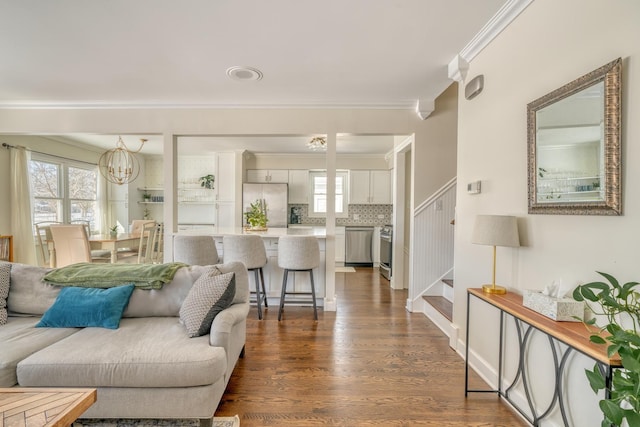 living room featuring a notable chandelier, dark hardwood / wood-style flooring, and ornamental molding